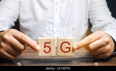 A man holds wooden blocks with the word 5G. High-speed mobile Internet. New generation networks. Fifth generation cellular network technology Stock Photo