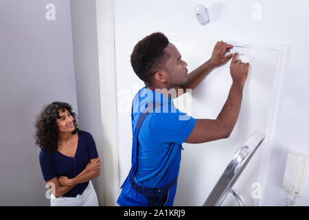 Technician Installing Security System Door Sensor On Wall Stock Photo
