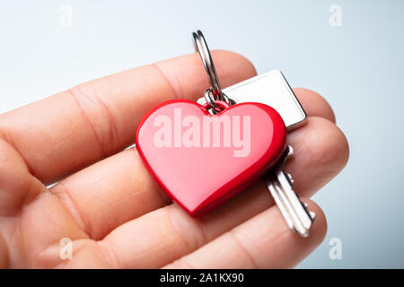 Close-up Of A Person's Hand Holding Red Heart Shape Key Chain With Key Stock Photo