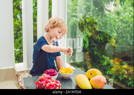 Little cute boy eating mango on the terrace Stock Photo