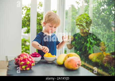 Little cute boy eating mango on the terrace Stock Photo