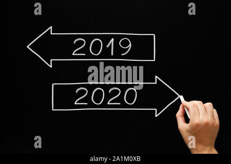 Hand drawing New Year beginning arrows concept with chalk on blackboard. Going ahead to year 2020 and leaving the year 2019 behind. Stock Photo