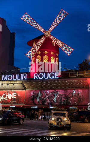 The Moulin Rouge in Paris, France at night with classic Citroen Traction 11CV vintage car in the foreground. Stock Photo