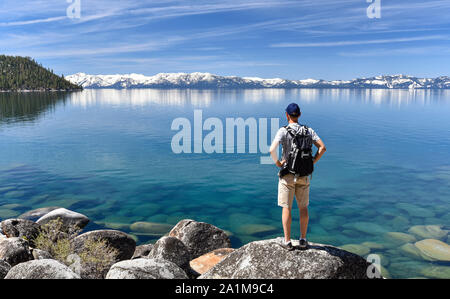 Man standing on a boulder and contemplating the Lake Tahoe, in Nevada, USA.
