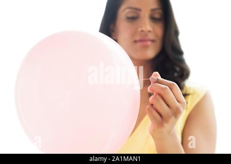 Woman popping pink balloon. Conceptual image for bloated stomach. Stock Photo