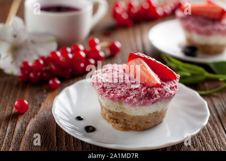 Raw vegan mini cheesecakes with strawberry on wooden table Stock Photo