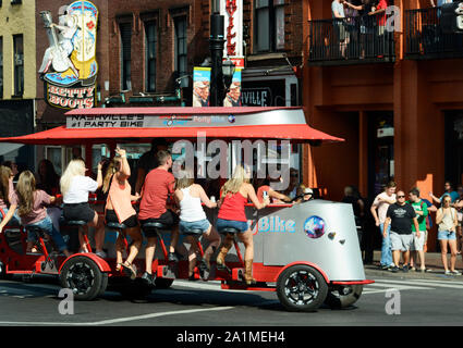 Young men and women peddle a Party Bike along a street in Nashville, Tennessee's entertainment district Stock Photo