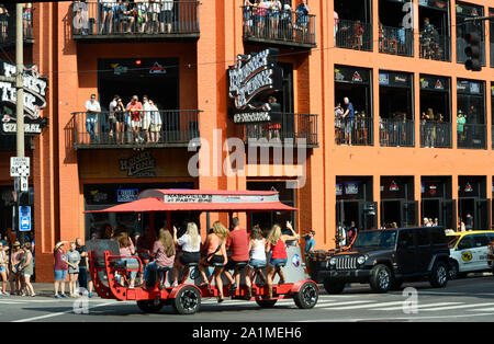 Young men and women peddle a Party Bike along a street in Nashville, Tennessee's entertainment district Stock Photo