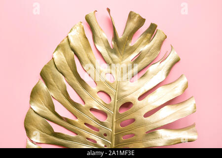 Golden tropical palm leaf Monstera on pastel luxury pink . Abstract pattern for design and space for text. Stock Photo