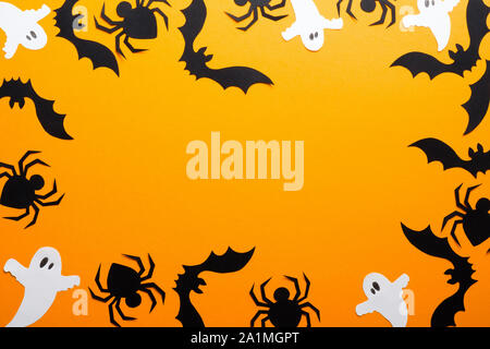 Happy halloween holiday concept. Frame made of Halloween decorations, spiders, bats, ghosts on orange background. Halloween party greeting card mockup Stock Photo