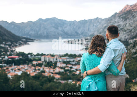 A couple of tourists hug and enjoy the beautiful view of the Kotor Bay and the city of Kotor in Montenegro. Travel together. Stock Photo