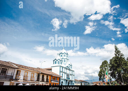 Colourful traditional houses and a blue & white Catholic church on the main plaza of Filandia, a typical Colombian town in the Quindio coffee region Stock Photo