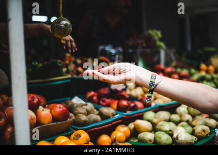 Tourist traveler pays for produce at a fruit and vegetable market in Colombia - South America exotic fruits