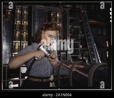 Operating a hand drill at the North American Aviation, Inc., [a] woman is in the control surface department assembling a section of the leading edge for the horizontal stabilizer of a plane