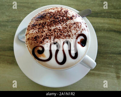 A cup of Cappuccino showing a very clever chocolate design on top. Stock Photo
