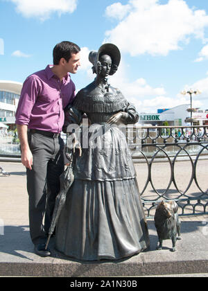 A tourist poses with the 'Chekhov lady with her dog' sculpture by Vladimir Ivanovich Zhbanov in Minsk Stock Photo