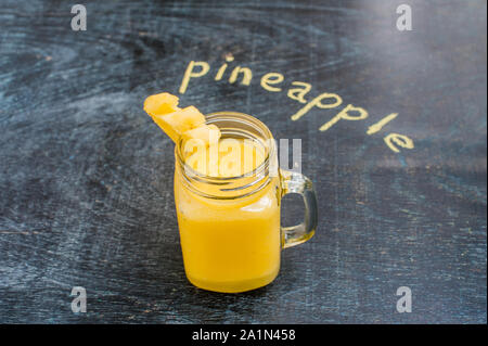 Pineapple cocktail with a slice of on wooden background and inscription in chalk . Tropical concept Stock Photo