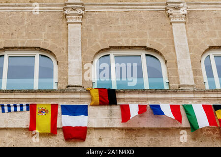 Flags of European countries hanging from a balcony in the Italian city of Matera.