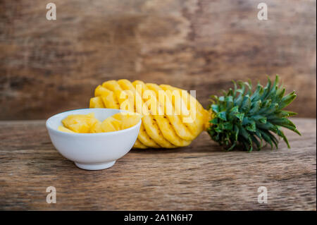 Pineapple slices and pineapple shelled on the old wooden background Stock Photo