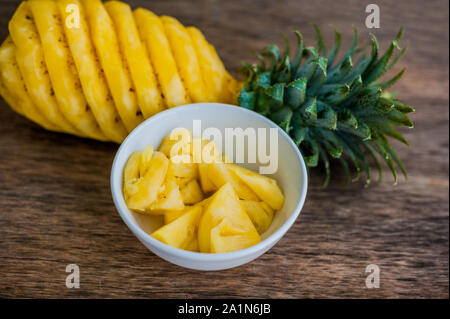 Pineapple slices and pineapple shelled on the old wooden background Stock Photo
