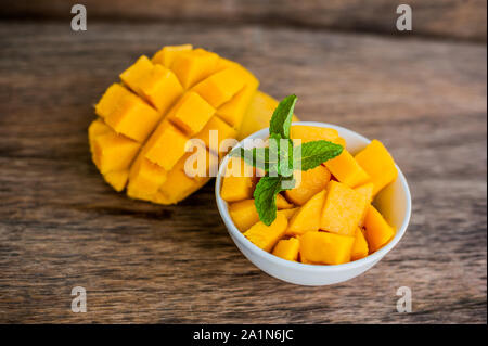 Mango fruit and mango cubes on the wooden table. Stock Photo
