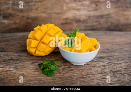 Mango fruit and mango cubes on the wooden table. Stock Photo