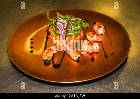 Dates prunes in a ham coat with salad served on a plate Stock Photo