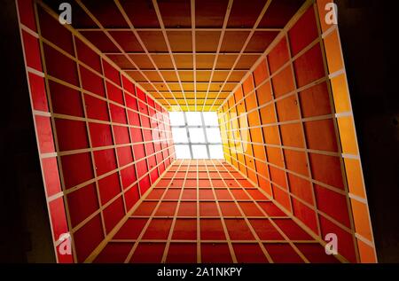 Abstract perspective of vertical lobby ceiling with skylight and strong geometry and symmetry and dramatic colours as background Stock Photo
