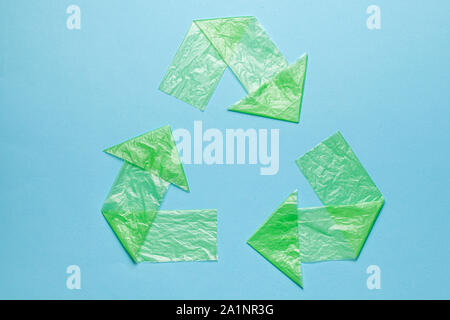 Sign recycling plastic from green bags on blue background. Environmental pollution by disposable bags, recycling. Stock Photo