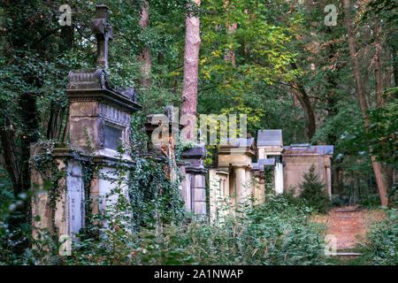 Weathered old tombstones on the Suedwest Kirchhof cemetery in Stahnsdorf, Germany in the woods Stock Photo