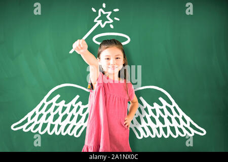 little girl standing against chalkboard and magic   concept Stock Photo