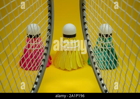 Badminton rackets and colorful feathered shuttlecocks in blue, yellow and pink Stock Photo