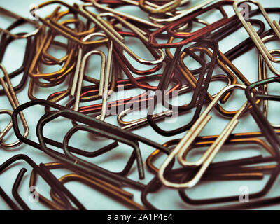 Colorful paperclips on light blue background. Old photo effect. Stock Photo