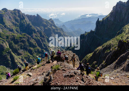 PICO DO AREEIRO, MADEIRA - SEPTEMBER 2019: Group of tourists hiking in the mountains of Madeira from 'Pico do Areeiro' to 'Pico Ruivo' on a cloudy sum