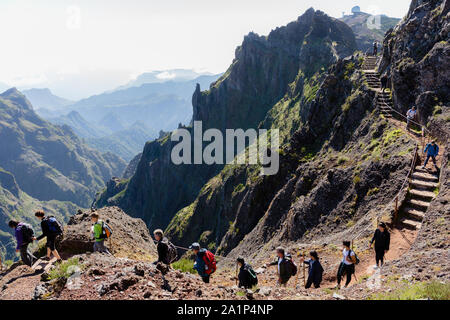 PICO DO AREEIRO, MADEIRA - SEPTEMBER 2019: Group of tourists hiking in the mountains of Madeira from 'Pico do Areeiro' to 'Pico Ruivo' on a cloudy sum