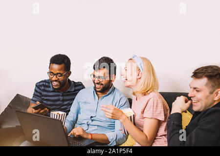 Happy diverse friends students group looking at laptop having fun watching comedy movie, online show, funny video. Multiracial young people laughing u Stock Photo