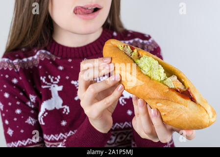 Cropped close up photo portrait of happy smiling satisfied tongue-out girl  holding long big burger in hands preparing for biting isolated grey color Stock Photo