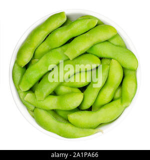 Edamame, green soybeans in the pod, in white bowl. Unripe soya beans, also Maodou. Glycine max, a legume, edible after cooking and rich protein source Stock Photo
