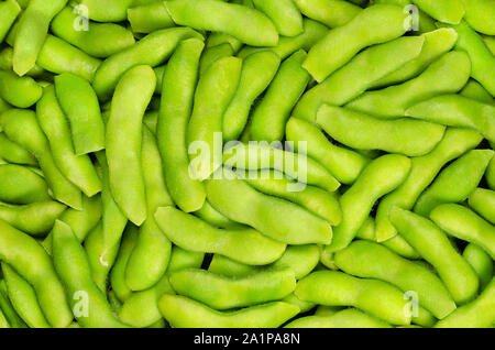 Edamame, green soybeans in the pod, background. Unripe soya beans, also Maodou. Glycine max, a legume, edible after cooking and a rich protein source. Stock Photo