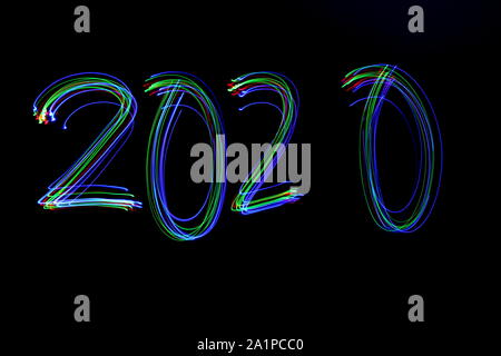 Long exposure photograph of the digits '2020' in neon multi colour against a black background. Light painting photography. Stock Photo