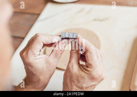 Hands make a round clay product with the words "love". Stock Photo