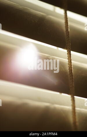 closed horizontal blinds through which the sun shines Stock Photo