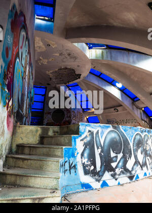 Abandoned interior of concrete building with dome and blue glass windows from below at ancient Hue water park, Vietnam Stock Photo