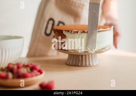 Man's hand levels cream on cake, cake decor. Making Sponge cake process. Stock Photo