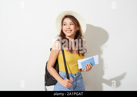 Portrait of young woman wearing trendy outfit, straw hat, travel with backpack  and holding flight ticket, passport Stock Photo