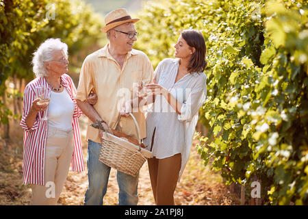 Grape Vineyard fields. Grape harvesting. Happy Family toasting and drinking wine and having fun outdoors. Stock Photo