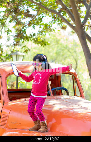 Little girl listening to music on the tablet with her headphones in the truck car Stock Photo