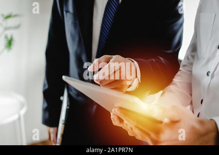 Job training. new manager boss mentor standing teaching online work with mobile tablet to young intern apprentice learning statistics chart Stock Photo