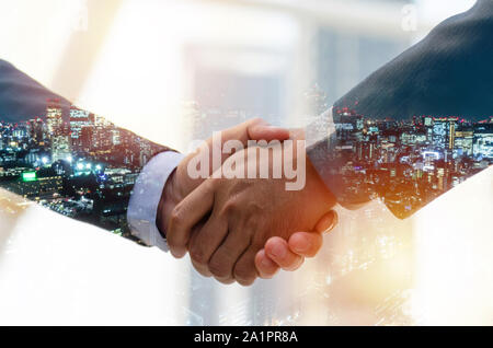 Partnership. double exposure image of investor business man handshake with partner for successful meeting deal with during sunrise and cityscape Stock Photo