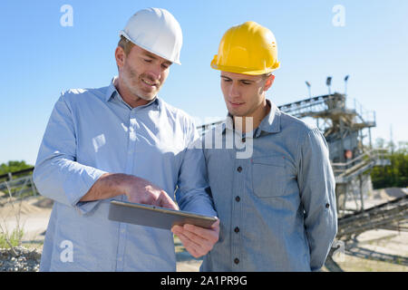 two builders outdoors looking at tablet Stock Photo